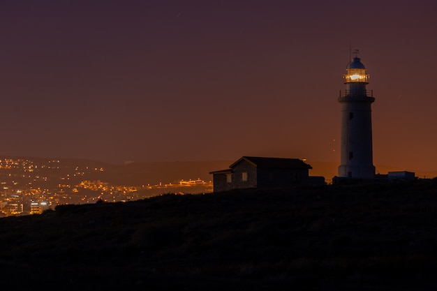 無料の写真 キプロスで夜に撮影された灯台と丘の上の家の美しい景色