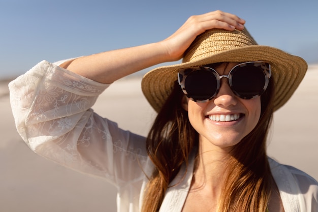 Free Photo Beautiful Woman In Hat And Sunglasses Standing On Beach In The Sunshine