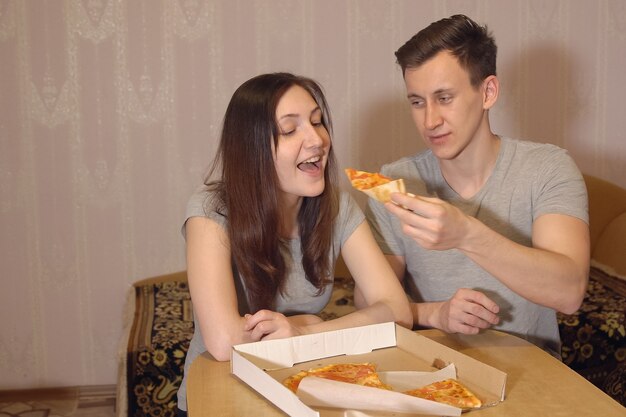 Premium Photo | Beautiful woman and man eating pizza at home.