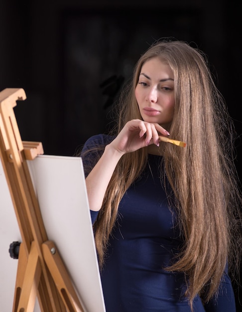 Premium Photo | Beautiful woman standing near easel