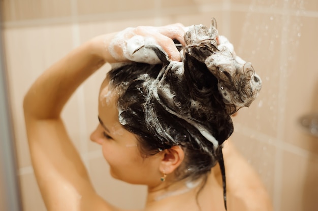 Beautiful woman washing hair with shampoo Premium Photo