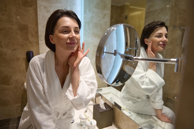 Premium Photo Beautiful Woman In White Bathrobe Smiles Looking At Her Mirror Reflection