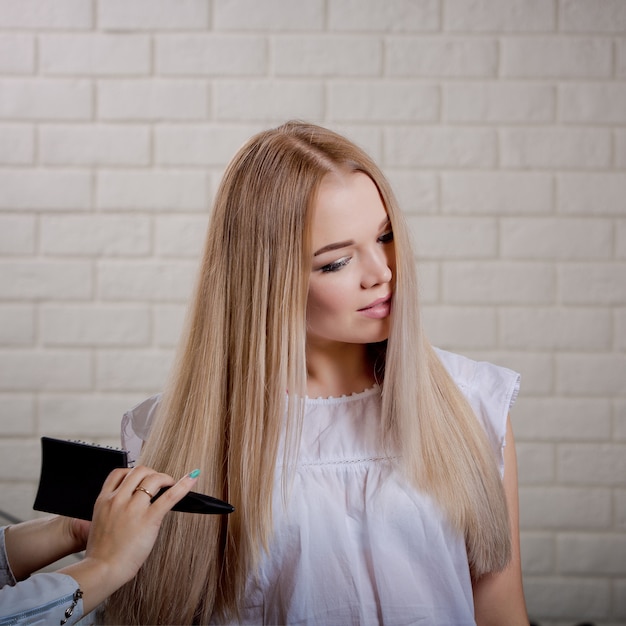 Premium Photo Beautiful Young Blonde Combs Her Hair After Dyeing And Styling In A Beauty Salon