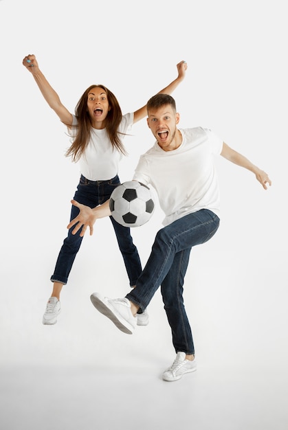 白いスタジオの背景に分離された美しい若いカップルの肖像画 顔の表情 人間の感情 広告 賭け スポーツの概念 サッカーやサッカーをしている男女 無料の写真