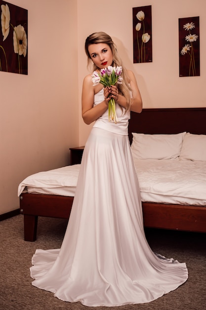 꽃과 함께 호텔에서 흰 드레스에 아름 다운 젊은 여자 프리미엄 사진