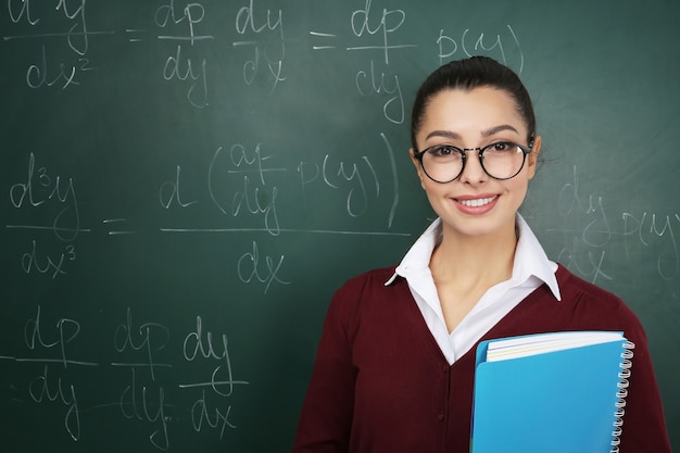 Premium Photo | Beautiful young teacher near blackboard in classroom