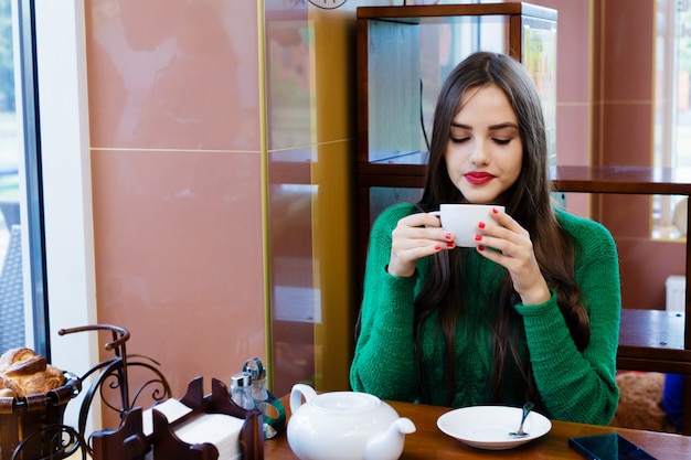 Beautiful young woman drinking tea in cafe Premium Photo