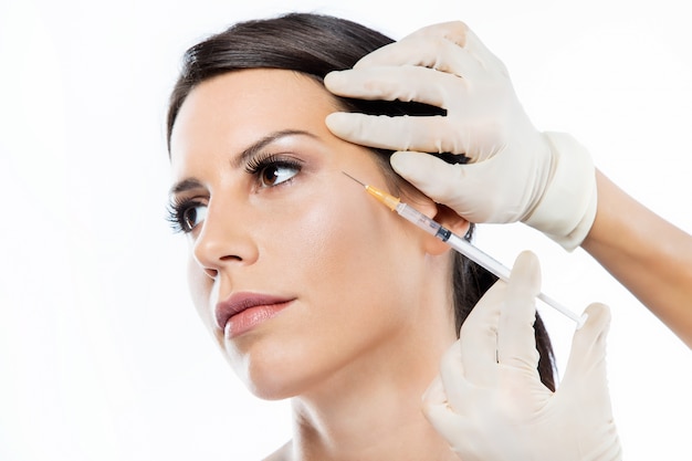 Beautiful young woman getting botox cosmetic injection in her face