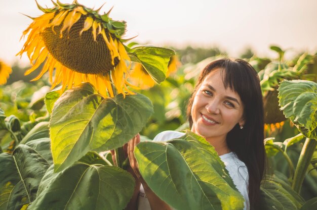 ひまわり畑で美しい若い女性 太陽の下で若い女性の肖像画 花粉アレルギーのコンセプト プレミアム写真