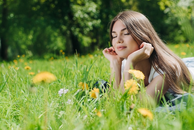 Premium Photo | Beautiful young woman laying on grass with dandelion ...