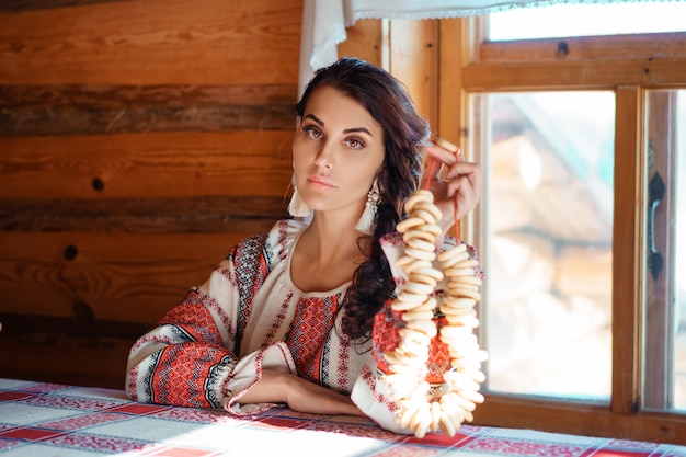 Premium Photo | Beautiful young woman in national costume sitting in a hut