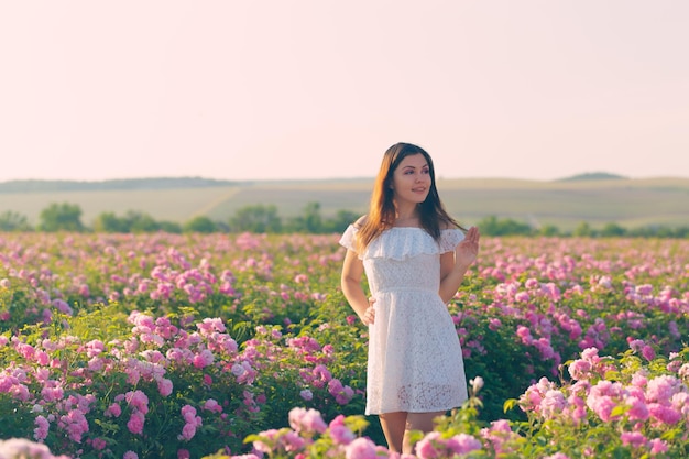 Premium Photo | Beautiful young woman posing near roses in a garden.