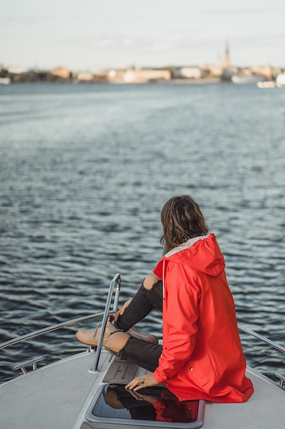 Beautiful young woman in a red raincoat rides a private yacht. stockholm, sweden Free Photo
