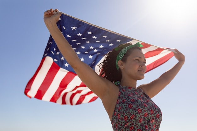 Beautiful young woman waving american flag on beach in the ...