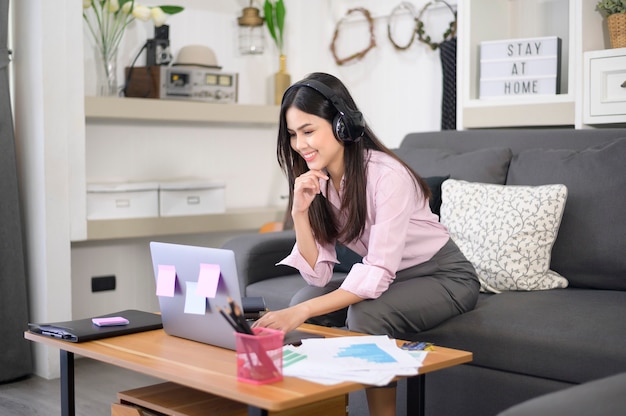 A beautiful young woman wearing headset is making video conference call via computer at home , business technology concept . Premium Photo