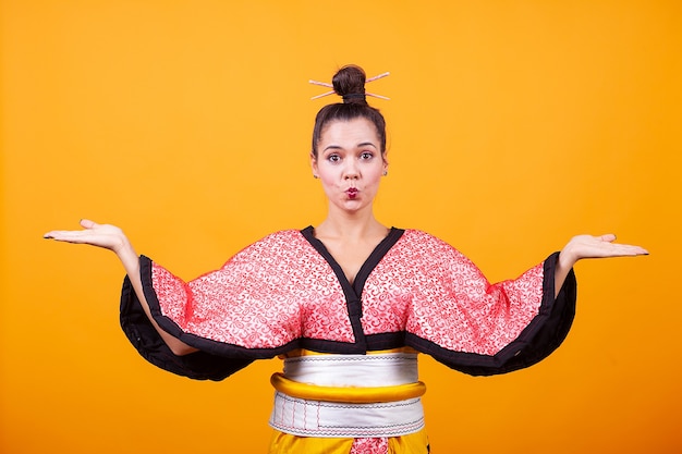 Beautiful young woman wearing japanese costume over yellow background Free Photo