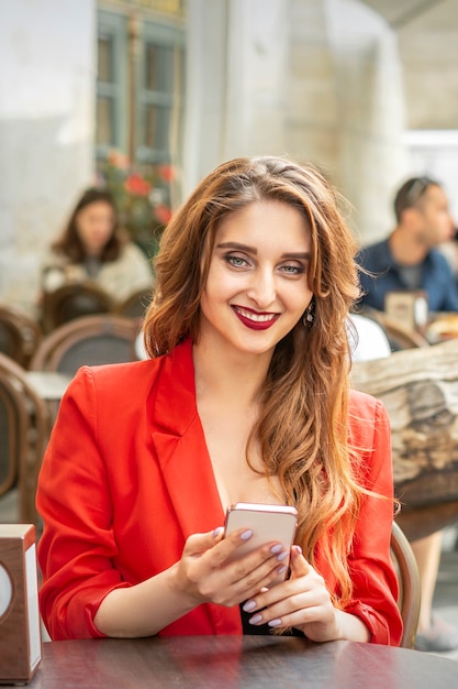 Premium Photo Beautiful Young Woman With Smartphone Sitting At The Table In Cafe Outdoors 5909