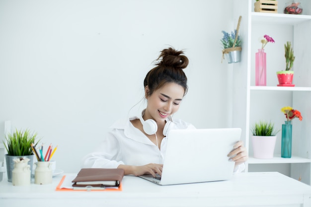 Beautiful young woman working on her laptop in her room. Free Photo