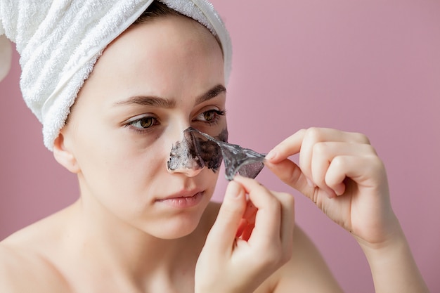 Beauty cosmetic peeling. closeup beautiful young female with black peel off mask on skin Premium Photo