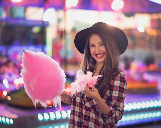 Premium Photo | Beauty girl with a cotton candy in a fair with many lights