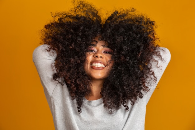 アフロの髪型と魅力のメイクとアフリカ系アメリカ人の女性の美しさの肖像画 ブラジルの女性 混血 巻き毛 髪のスタイル 黄色の壁 プレミアム写真