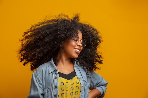 アフロの髪型と魅力のメイクとアフリカ系アメリカ人の女性の美しさの肖像画 ブラジルの女性 混血 巻き毛 髪のスタイル 黄色の壁 プレミアム写真