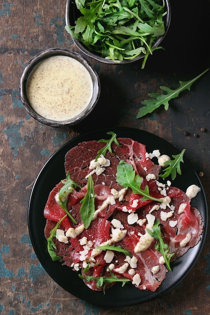 Premium Photo | Beef carpaccio with arugula and sauce