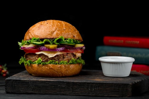 Beef cotlet burger with sauce on a wooden board Free Photo