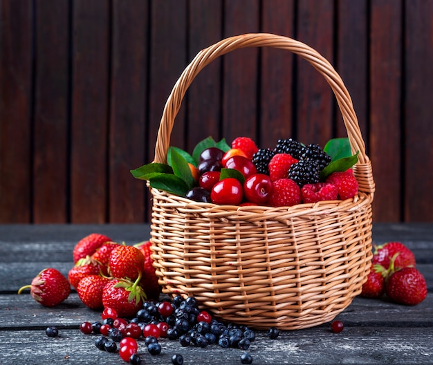 Berries mix in basket on rustic wooden background Premium Photo