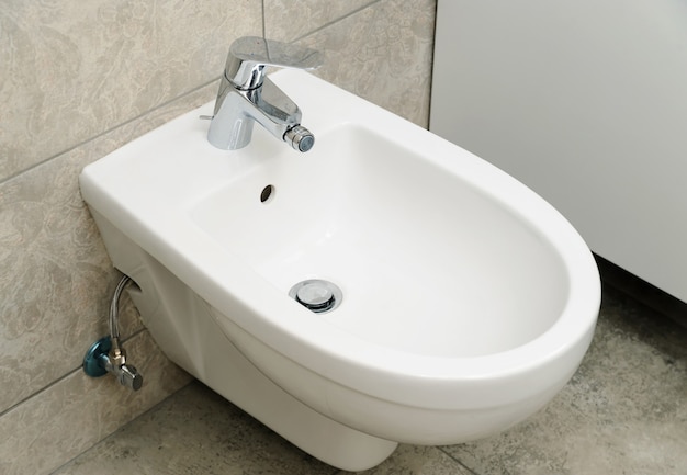 Premium Photo | Bidet with water faucet fixed on the wall.