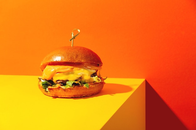 Premium Photo | Big burger with cheese on bright orange and yellow ...