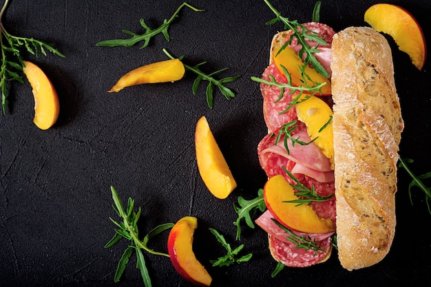 Big sandwich with ham, salami, nectarine and arugula. Photo  Premium Download