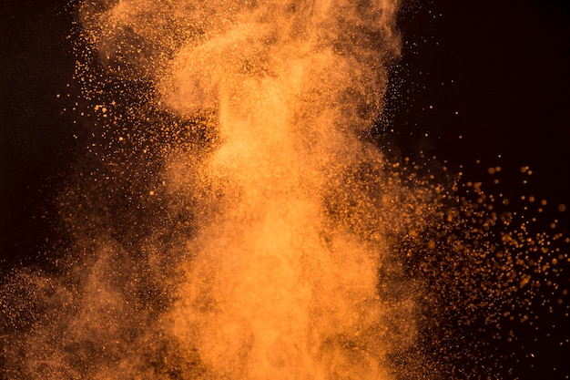 Big splash of orange makeup powder on dark background Free Photo
