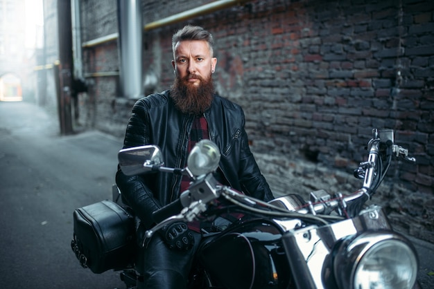 Premium Photo | Biker in leather jacket sitting on classical chopper ...