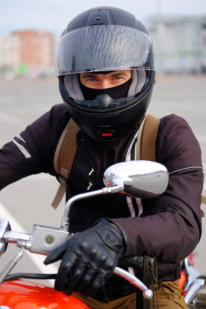 Biker man or guy-racer in a protective helmet sitting on a motorcycle