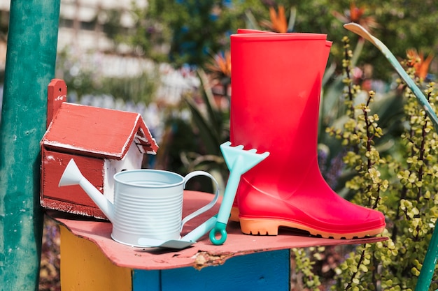 Free Photo Birdhouse With Red Wellington Boots Watering Can Gardening Tools In The Garden