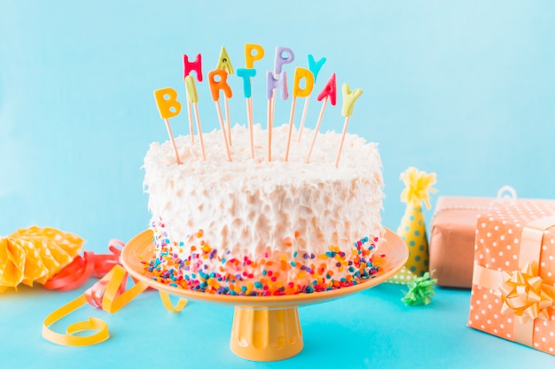 Birthday cake with gift and accessories on blue background Free Photo