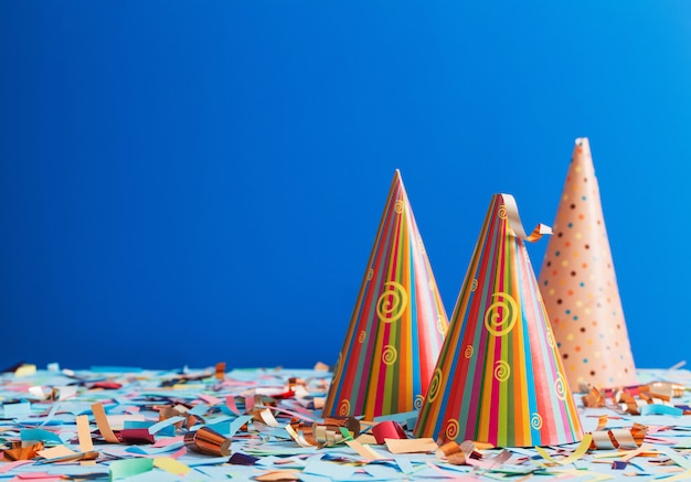 Premium Photo | Birthday hat and confetti on blue background