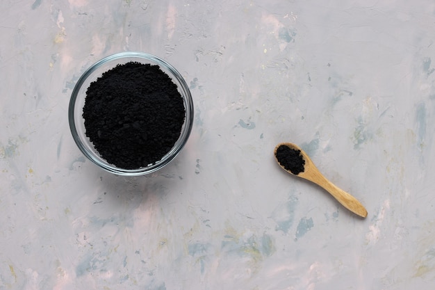 Premium Photo | Black activated charcoal powder in a glass bowl and ...