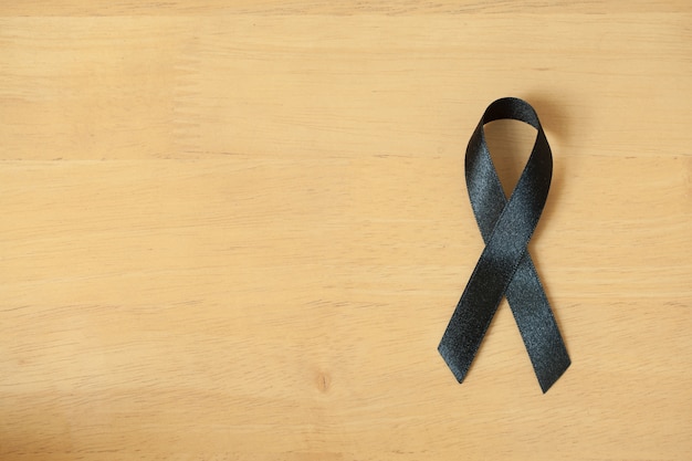 Premium Photo | Black awareness ribbon on wooden background. mourning ...