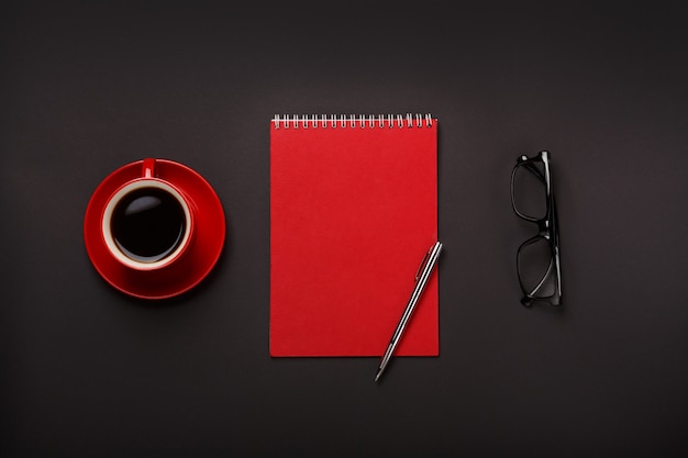 黒の背景赤コーヒーカップメモ帳ペングラス空の場所デスクトップ プレミアム写真