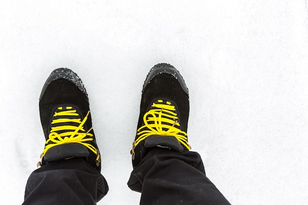 Black boots with yellow laces on the snow
