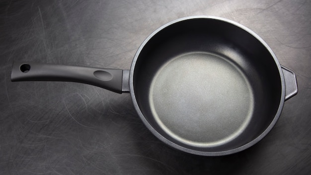 Black frying pan with non-stick teflon coating on dark background Premium Photo