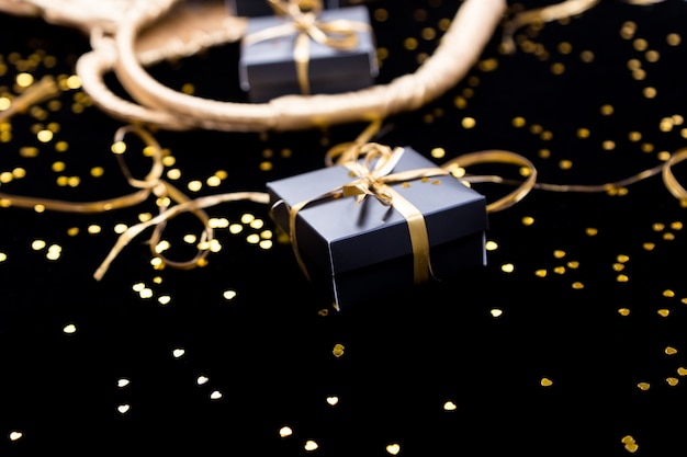 Premium Photo | Black gift boxes with gold ribbon pop out from golden ...
