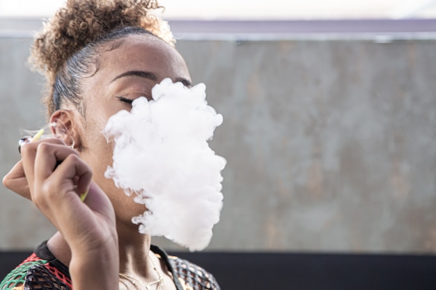 Premium Photo Black Girl With Curly Hair Smoking With A Steamer And Blowing A Deep Smoke