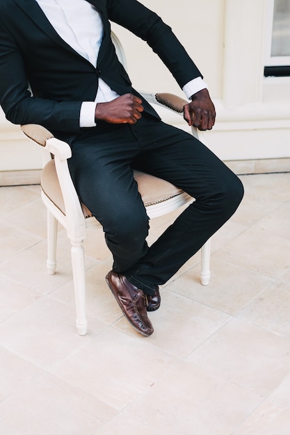 黒の革張りの椅子新郎に座っているビジネススーツの黒人男性 プレミアム写真