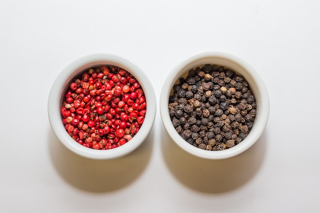 Black and red pepper on white table. seasoning and species ingredients concept . composition of culinary ingredients. spices arranged in white pots. Premium Photo