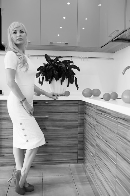 Premium Photo Black And White Photo Of Blonde Girl Posing On Camera Standing In Kitchen