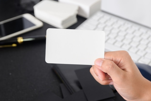 Blank Business Card Mock Up In Hand On Blurre Office Desk