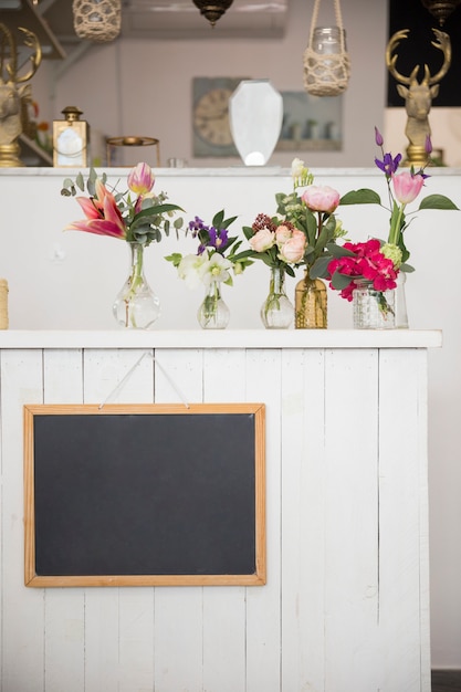 Blank Slate Hanging On Wall With Beautiful Flower Vases In The